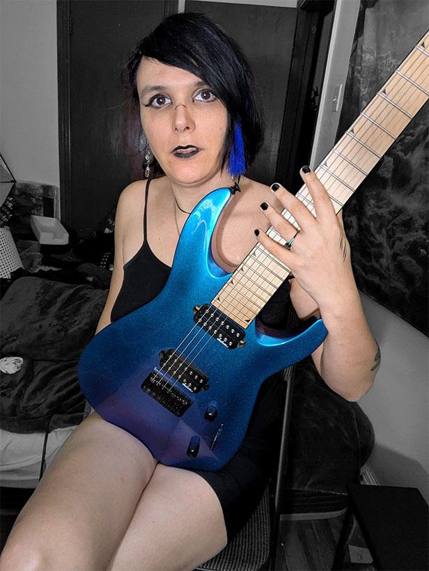 Lillycue, Musician, Woman, Trans Woman, Goth Aesthetic, Makeup, Sitting, Holding Guitar, Blue Electric Guitar, Seven String Guitar, Metal Music, Dragon Of Darkness